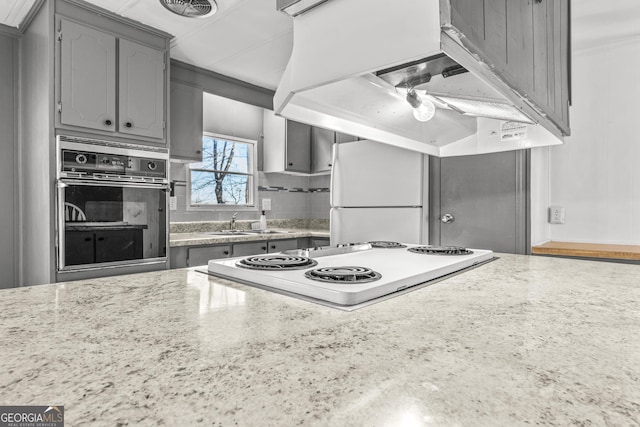 kitchen featuring white appliances, sink, decorative backsplash, gray cabinets, and extractor fan