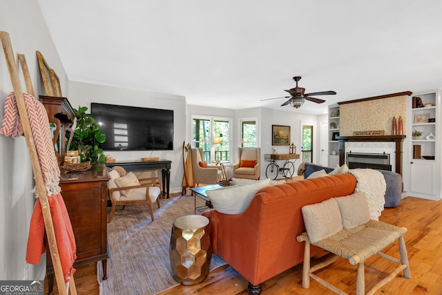 living room featuring ceiling fan, hardwood / wood-style floors, and a large fireplace