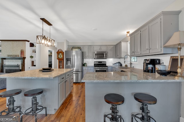 kitchen with pendant lighting, light hardwood / wood-style floors, sink, a breakfast bar area, and stainless steel appliances