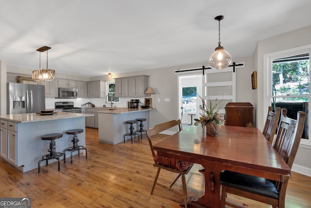 dining space featuring light hardwood / wood-style floors, sink, and a barn door