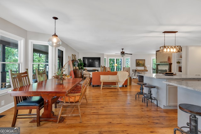 dining area featuring light wood-type flooring, ceiling fan, and plenty of natural light