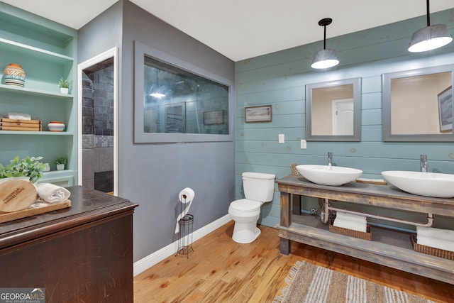 bathroom with built in shelves, vanity, wood walls, hardwood / wood-style flooring, and toilet