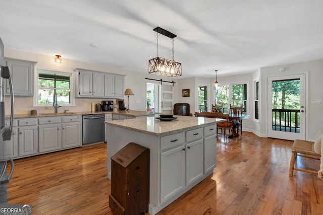 kitchen featuring a barn door, stainless steel dishwasher, a kitchen island, and light hardwood / wood-style floors