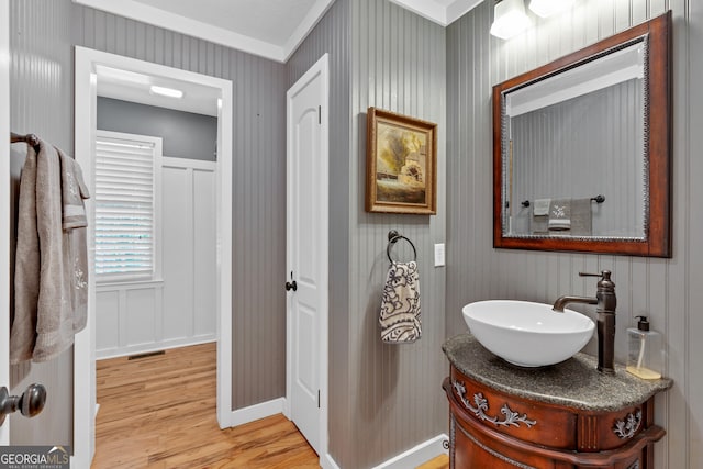 bathroom with ornamental molding, wood-type flooring, and vanity