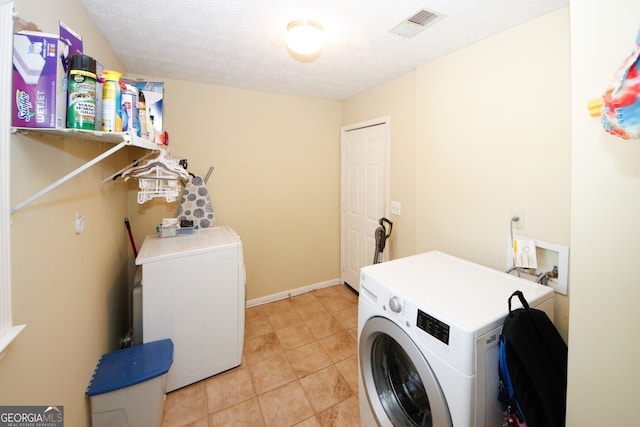 laundry room featuring independent washer and dryer, a textured ceiling, and light tile patterned floors