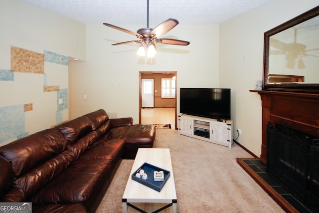 carpeted living room with a tiled fireplace and ceiling fan