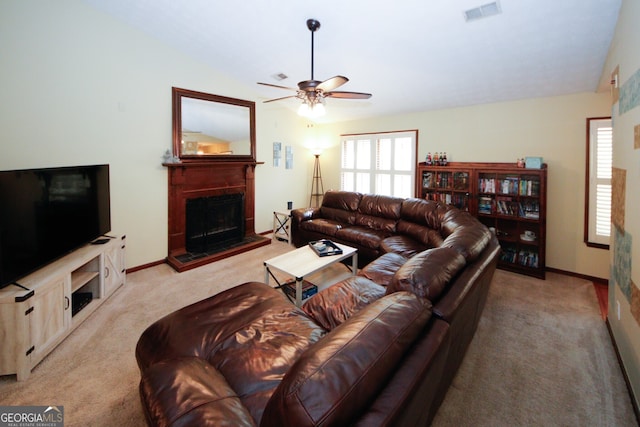 carpeted living room featuring lofted ceiling, a tile fireplace, and ceiling fan