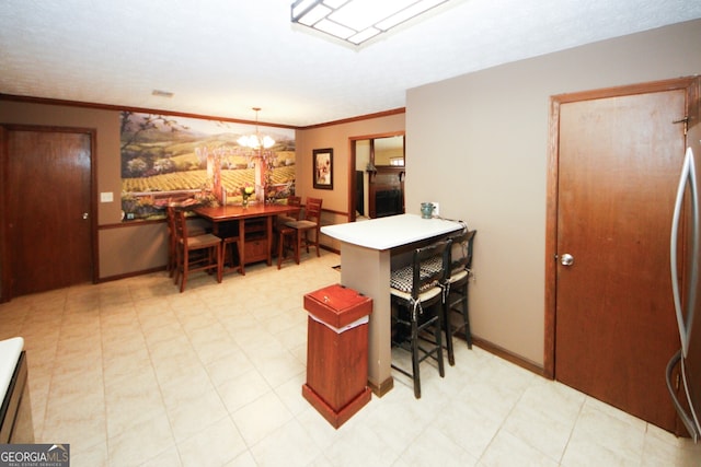 kitchen featuring kitchen peninsula, stainless steel fridge, hanging light fixtures, an inviting chandelier, and crown molding