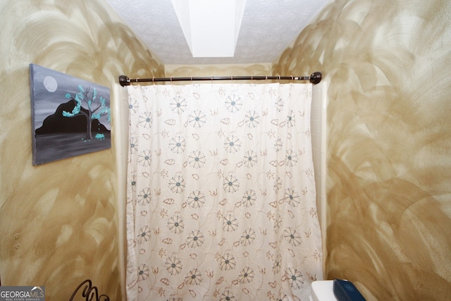 bathroom with a shower with shower curtain, a textured ceiling, toilet, and a skylight