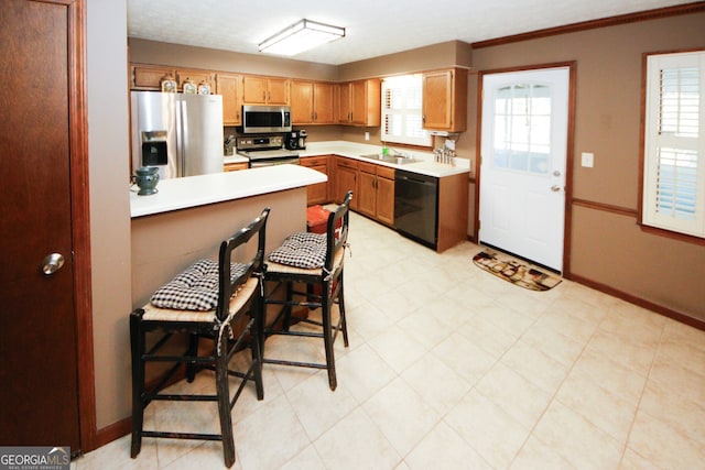 kitchen featuring appliances with stainless steel finishes, crown molding, sink, and a kitchen bar