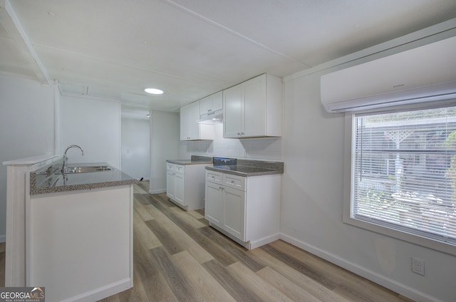 kitchen featuring white cabinets, light hardwood / wood-style flooring, sink, and a wall mounted AC