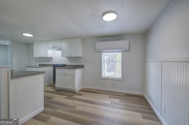 kitchen with light hardwood / wood-style flooring, white cabinets, and a wall mounted air conditioner