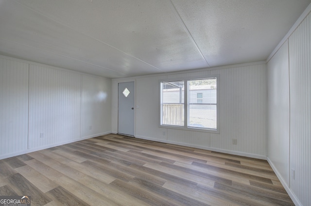 empty room featuring a textured ceiling and light hardwood / wood-style flooring