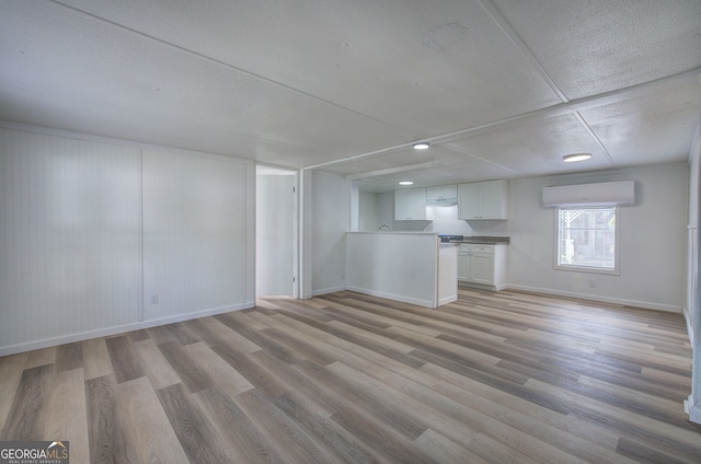 unfurnished living room featuring light hardwood / wood-style floors and an AC wall unit