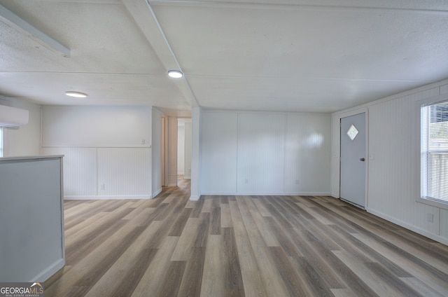 unfurnished living room featuring an AC wall unit and wood-type flooring