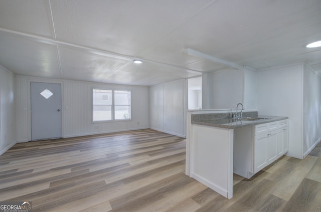 kitchen with light hardwood / wood-style flooring, sink, and white cabinetry