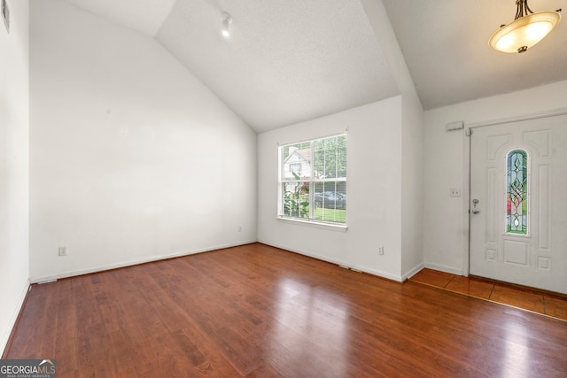 foyer featuring wood-type flooring, vaulted ceiling, and a textured ceiling