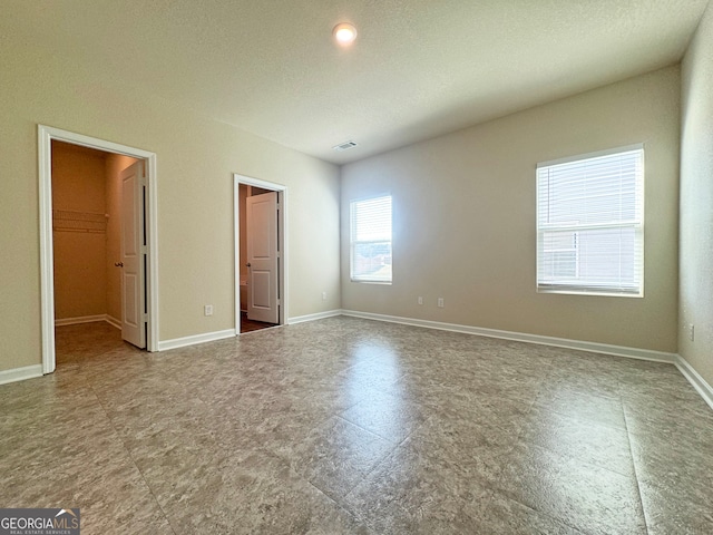 unfurnished bedroom with a textured ceiling, a closet, and a spacious closet