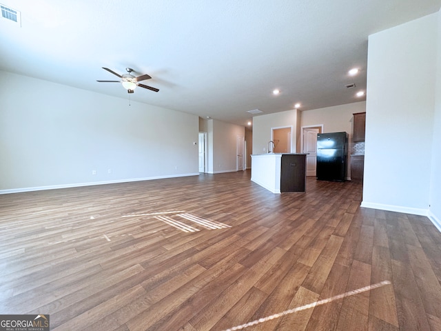 unfurnished living room featuring ceiling fan, dark wood-type flooring, and sink