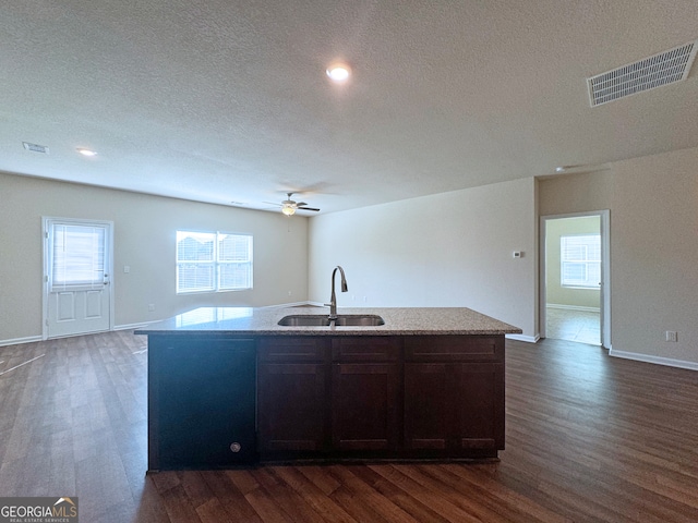 kitchen featuring dark brown cabinets, an island with sink, dark hardwood / wood-style floors, and sink