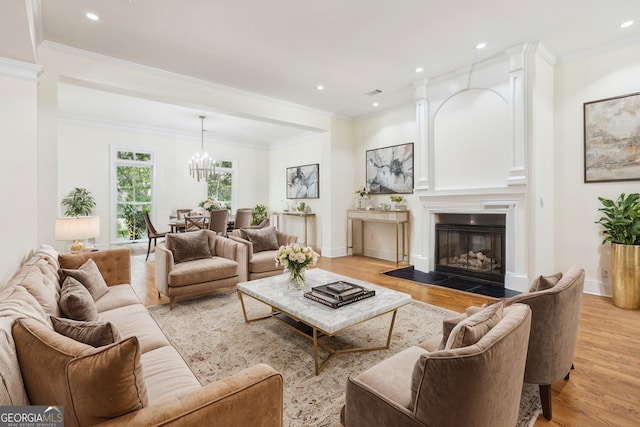 living room with light hardwood / wood-style floors, a chandelier, and ornamental molding