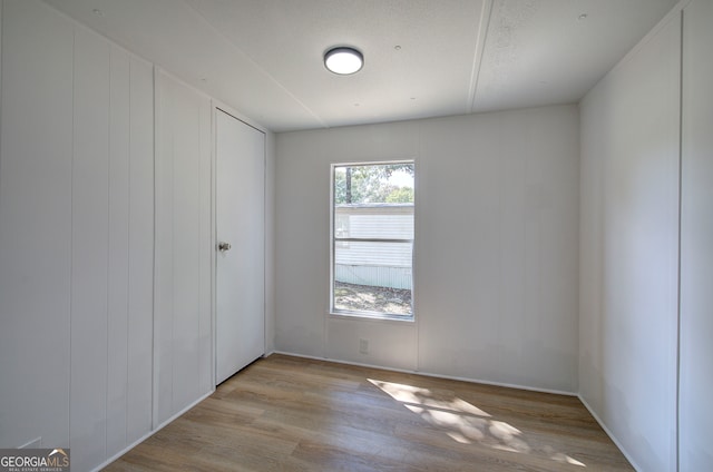 empty room with a textured ceiling and light hardwood / wood-style flooring