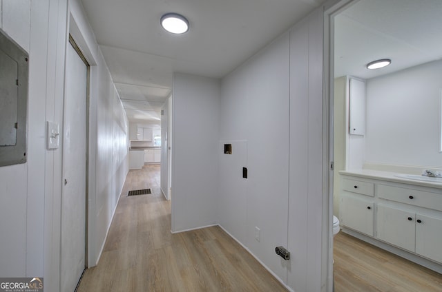 hall with electric panel, light hardwood / wood-style flooring, and sink