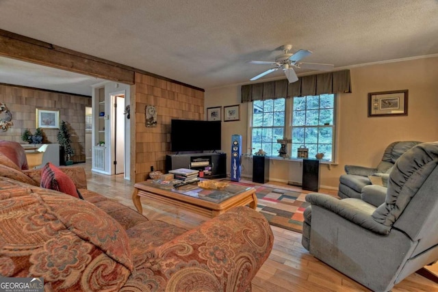 living room featuring a textured ceiling, crown molding, light hardwood / wood-style floors, and ceiling fan