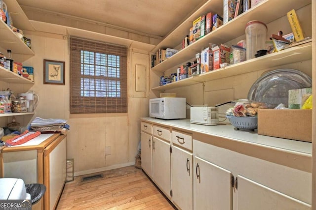 clothes washing area featuring wooden walls, light hardwood / wood-style floors, and crown molding