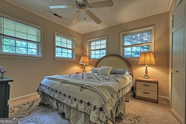 bedroom with ceiling fan, light colored carpet, a textured ceiling, and multiple windows