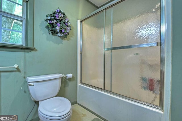 bathroom with bath / shower combo with glass door and toilet