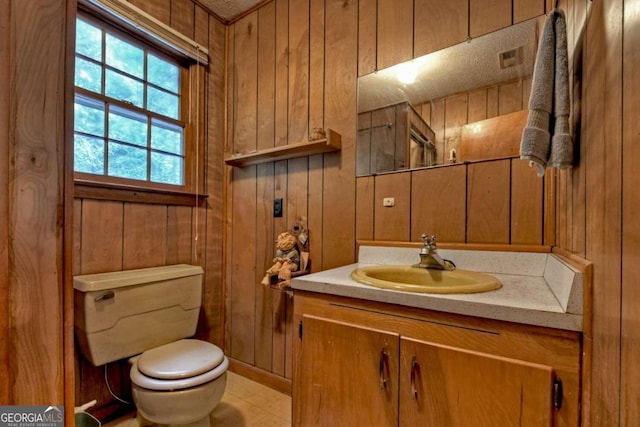 bathroom featuring wooden walls, vanity, and toilet