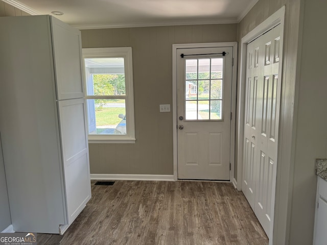 entryway with ornamental molding and hardwood / wood-style floors