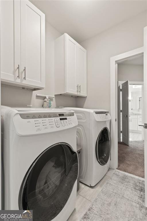 laundry area with light colored carpet, washer and dryer, and cabinets