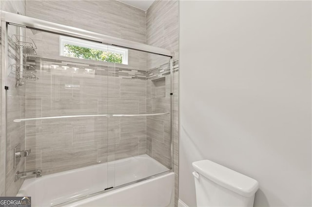 bathroom featuring bath / shower combo with glass door and toilet