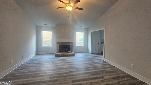 unfurnished living room featuring a fireplace, vaulted ceiling, ceiling fan, and dark wood-type flooring