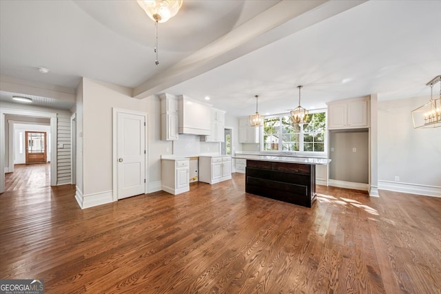 kitchen featuring white cabinets, decorative light fixtures, a kitchen island, and dark hardwood / wood-style flooring