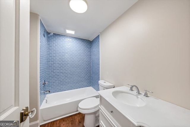 full bathroom featuring hardwood / wood-style flooring, tiled shower / bath combo, vanity, and toilet