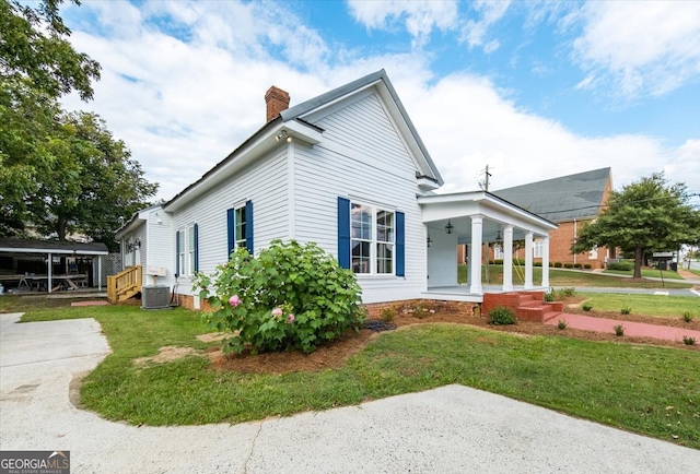 view of side of property with a yard, a porch, and central air condition unit