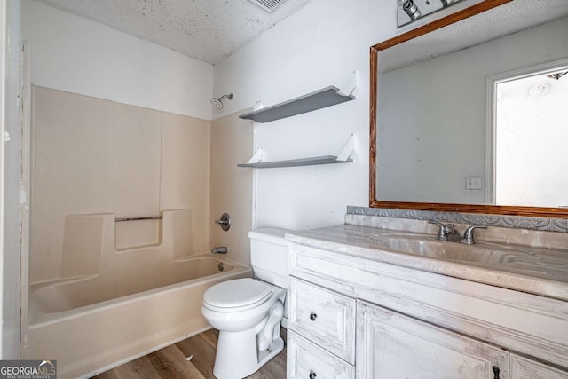 full bathroom with toilet, a textured ceiling, washtub / shower combination, wood-type flooring, and vanity