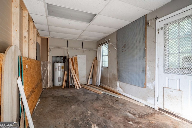 misc room with a paneled ceiling, water heater, and concrete flooring