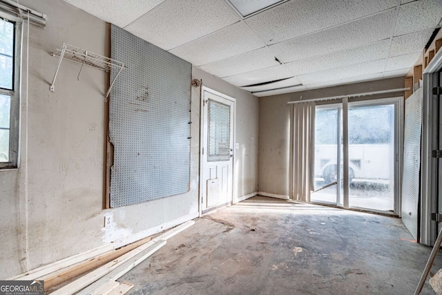 miscellaneous room featuring a paneled ceiling and concrete floors