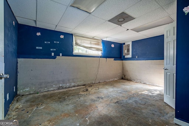 basement featuring a paneled ceiling and electric panel