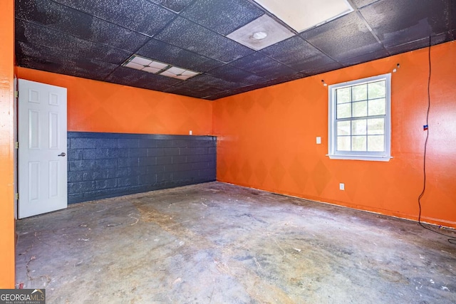 empty room with a paneled ceiling and concrete flooring