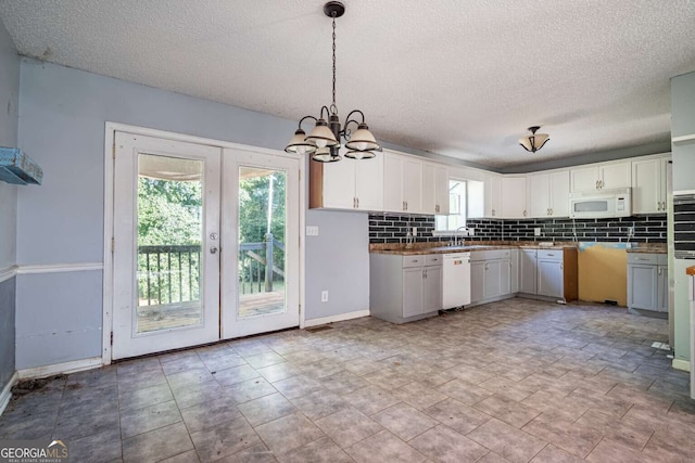 kitchen with white appliances, french doors, white cabinetry, and decorative light fixtures