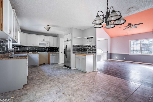 kitchen featuring white cabinets, stainless steel fridge, ceiling fan with notable chandelier, and sink