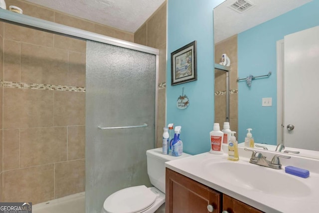 bathroom featuring a shower with door, toilet, a textured ceiling, and vanity