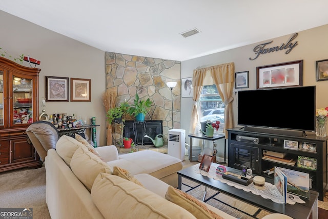 carpeted living room with a stone fireplace