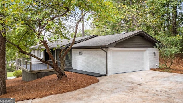 ranch-style home with an attached garage, a shingled roof, driveway, and brick siding