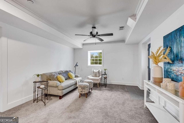 carpeted living area with a ceiling fan, baseboards, ornamental molding, and visible vents